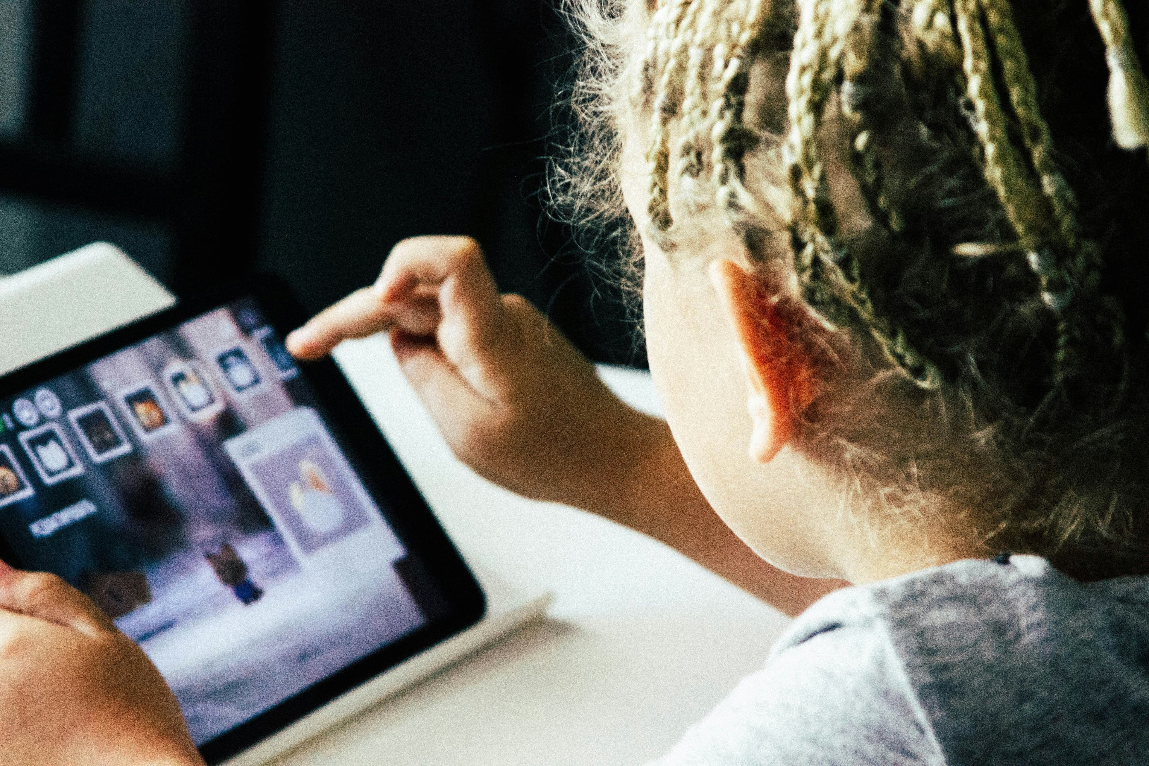 a young girl is playing a game on a tablet.